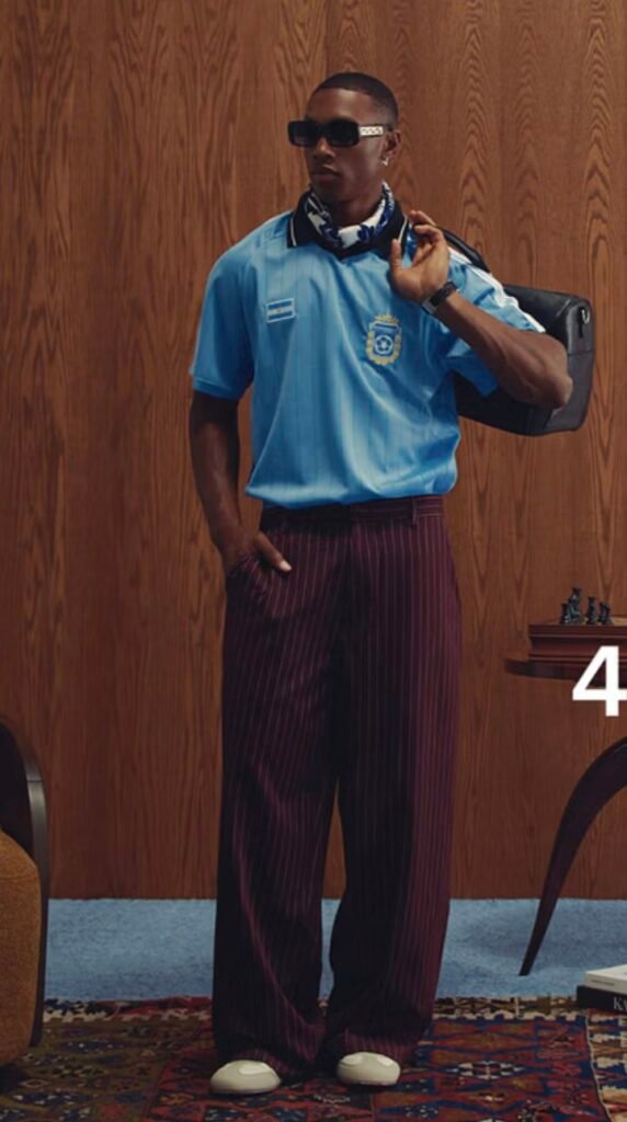 Man styling a light blue collared football jersey with tailored dress trousers in a elevated blokecore look.