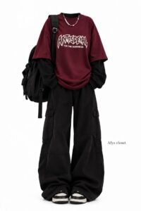 Layered college outfit featuring an oversized graphic tee worn over a white long-sleeve shirt with baggy jeans