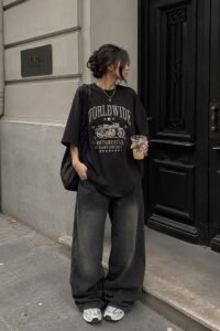 Oversized graphic tee front-tucked into light wash baggy jeans with sneakers