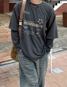 Streetwear layer look with a dark graphic t-shirt over a long-sleeve shirt paired with denim