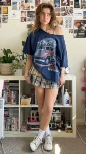 Street-chic college look featuring an oversized printed tee front-tucked into a pleated skirt
